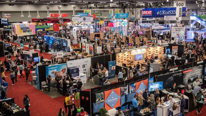 A wide overhead view of a large convention hall filled with booths.